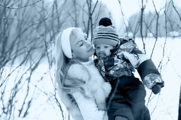 Uma jovem mãe caminha em um dia de inverno com um bebê em seus braços — Fotografia de Stock