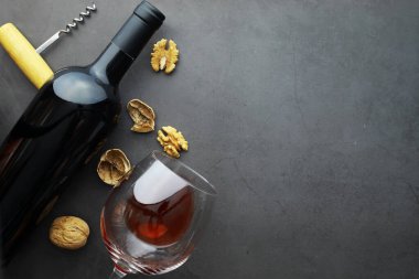 Şarap kadehi ve siyah şarap şişesi. Ceviz peyniri ve domates.