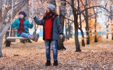 Kız sonbahar şehir parkında yaprak düşer. Genç güzel wi anne