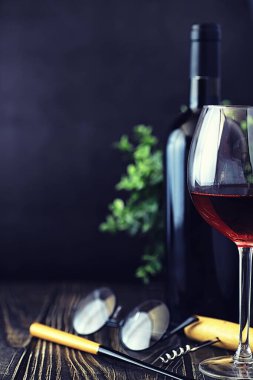 Masada bir bardak kırmızı kuru şarap. Siyah şişe ve bir bardak W