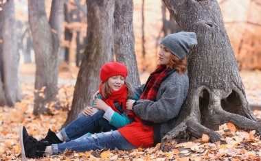 Kız sonbahar şehir parkında yaprak düşer. Genç güzel wi anne
