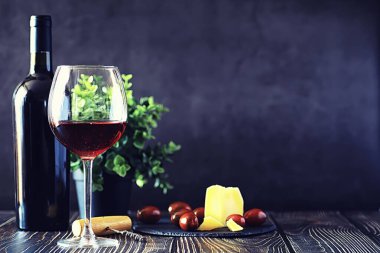 Masada bir bardak kırmızı kuru şarap. Siyah şişe ve bir bardak W