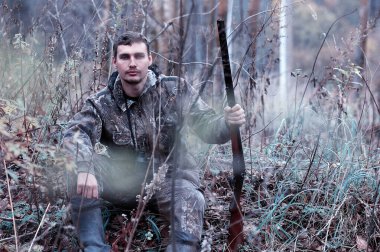 Kamuflaj ve bir sp üzerinde bir ormanda bir av tüfeği ile bir adam