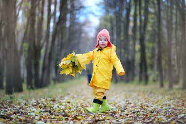 Çocuklar sonbahar parkında yürüyor. 
