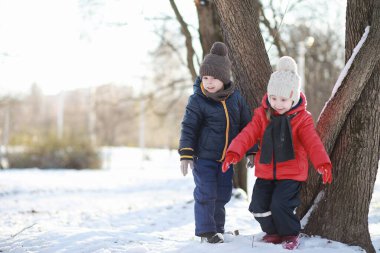 Kış parkında oynayan kalın elbiseli şirin çocuklar. 