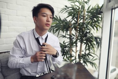 Genç Asyalı işadamı bir kafede bir ortak için bekliyor. Bu