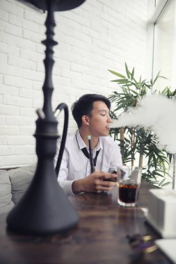 Genç Asyalı işadamı bir kafede bir ortak için bekliyor. Bu