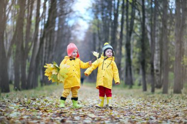 Çocuklar sonbahar parkında yürüyor. 