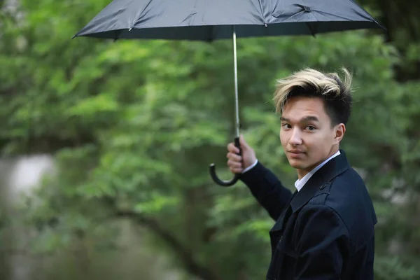 Våren regnigt väder och en ung man med ett paraply — Stockfoto