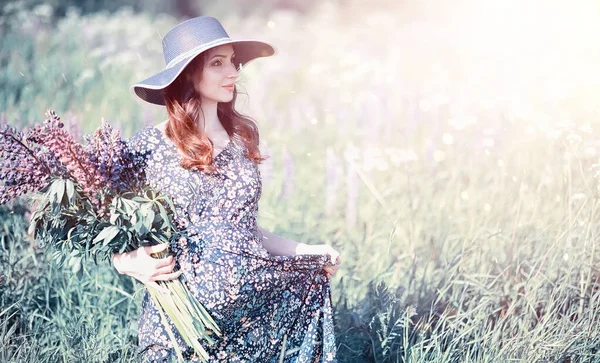 Chica embarazada en un campo con flores — Foto de Stock