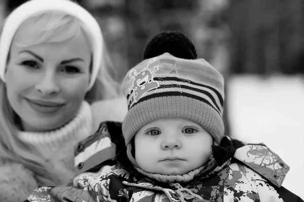 Een jonge moeder loopt op een winterdag met een baby in haar armen — Stockfoto