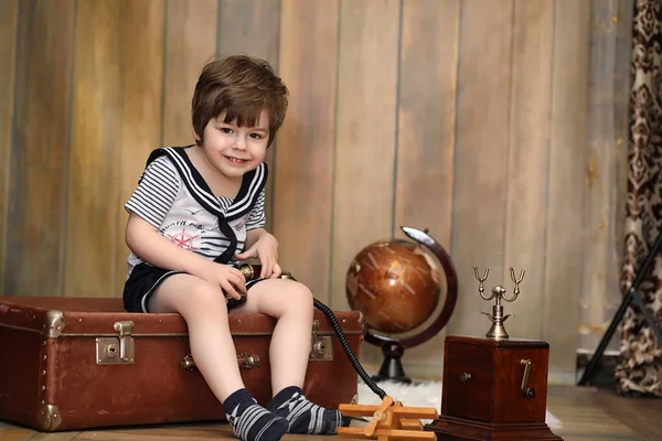 Un niño en un interior retro y un teléfono viejo se sienta en el suelo . — Foto de Stock