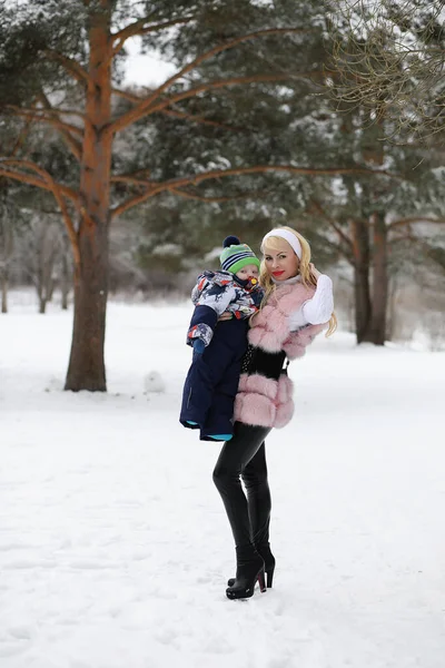 Ung mamma går på en vinterdag med en baby i famnen i th — Stockfoto
