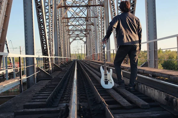 Homem com uma guitarra elétrica na paisagem industrial ao ar livre — Fotografia de Stock