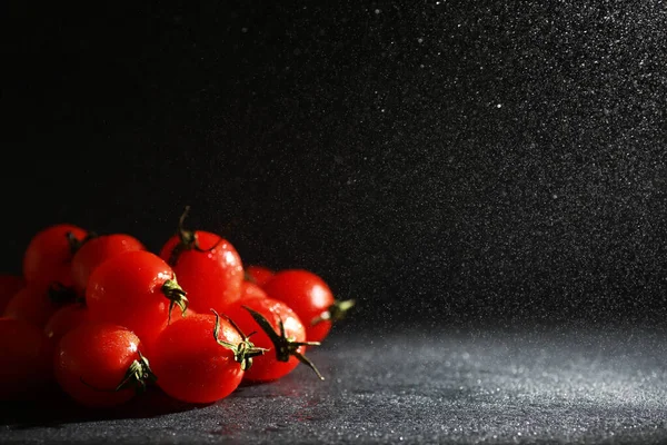 Sprey siyah bir arka plan üzerinde Kiraz domates