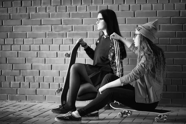 A young hipster girl is riding a skateboard. Girls girlfriends f — Stock Photo, Image