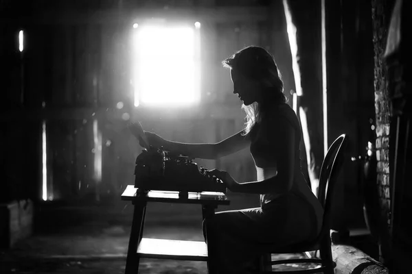 A girl prints on an old typewriter — Stock Photo, Image