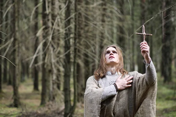 Um homem numa batina passa um ritual numa floresta escura. — Fotografia de Stock