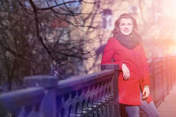 Hezká dívka na procházku v červeném kabátě ve městě — Stock fotografie
