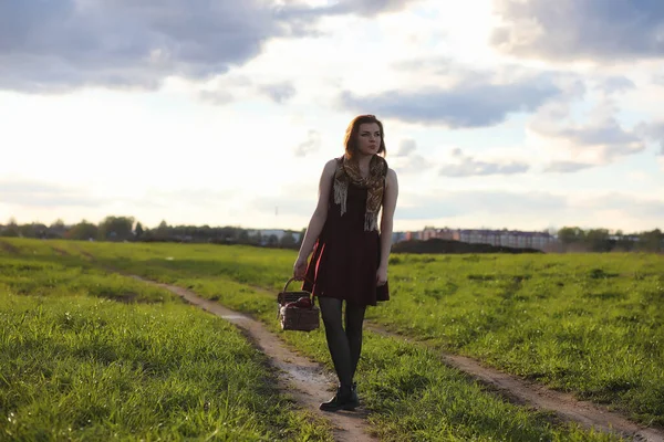 Ein Mädchen mit Hut bei einem Spaziergang im Park. ein Mädchen mit einem Korblauf — Stockfoto