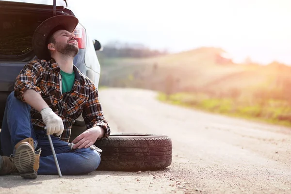 Man sitter på vägen av bilen — Stockfoto