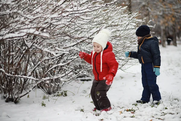 cute children in warm clothes playing in winter park