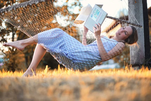 Schönes Mädchen in der Hängematte liest ein Buch — Stockfoto