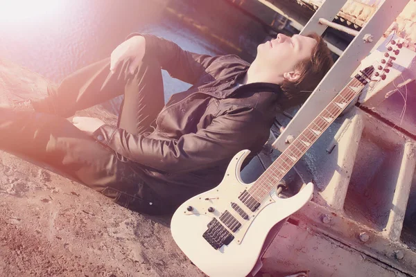 A man with an electric guitar on the railway. A musician in a le — Stock Photo, Image