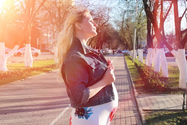 Une fille enceinte en promenade dans le parc. Fille avec un ventre dans le ci — Photo