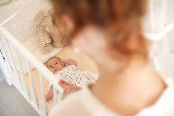 Novorozené roztomilé dítě leží v postýlce a vypadá matka — Stock fotografie