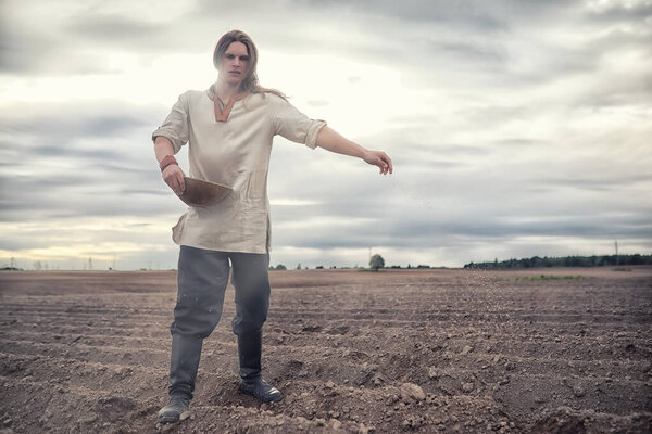 A young peasant sows the field with grain