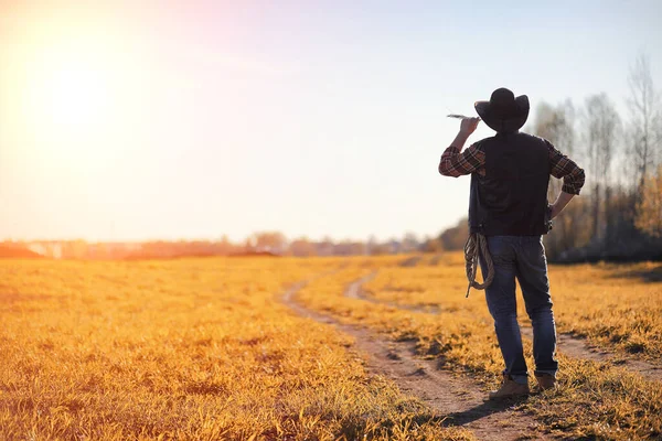 A man cowboy hat and a loso in the field. American farmer in a f — Stock Photo, Image