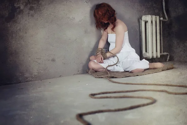 Young girl tied up on the floor. The abducted girl. The victim o Stock Picture