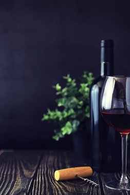 Masada bir bardak kırmızı kuru şarap. Siyah şişe ve bir bardak W
