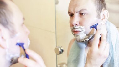 Bir adam sabahları banyoda tıraş oluyor.