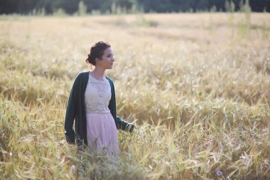 Genç anne yürüyerek buğday alanları içerisinde