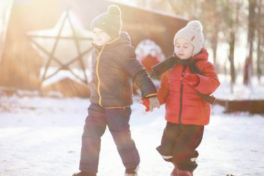Kış parkında oynayan kalın elbiseli şirin çocuklar. 