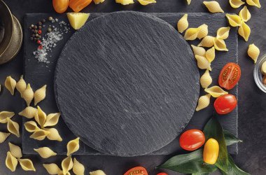 Siyah taş üzerine makarna kabukları. Allspi ile domates ve defne yaprağı