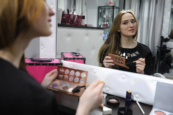 En ung flicka gör make-up i en skönhetssalong. Flickan i receptionen o — Stockfoto