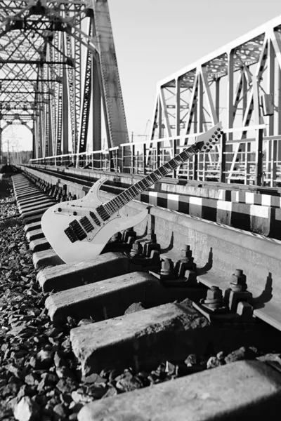 Guitarra elétrica preto e branco nas trilhas ferroviárias e pedra — Fotografia de Stock