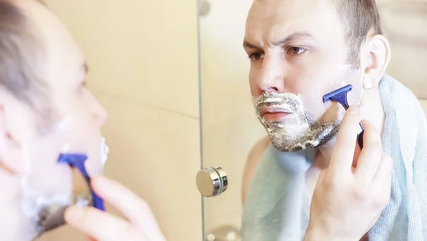 Um homem faz a barba na casa de banho pela manhã — Fotografia de Stock