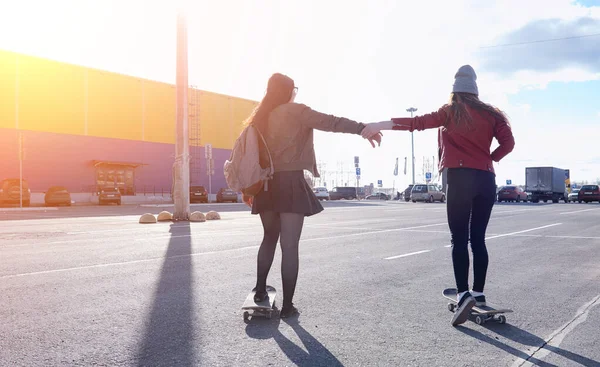 A young hipster girl is riding a skateboard. Girls girlfriends f — Stock Photo, Image