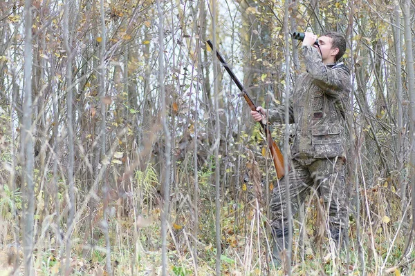 Homem em camuflagem e com armas em um cinto florestal em um hun primavera — Fotografia de Stock