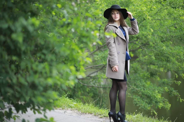 Chica joven en un abrigo en un parque de primavera — Foto de Stock