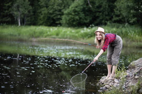 Menina junto ao rio com uma vara de pesca — Fotografia de Stock