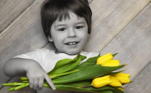 A small child with a bouquet of yellow tulips. A boy with a gift — Stock Photo, Image