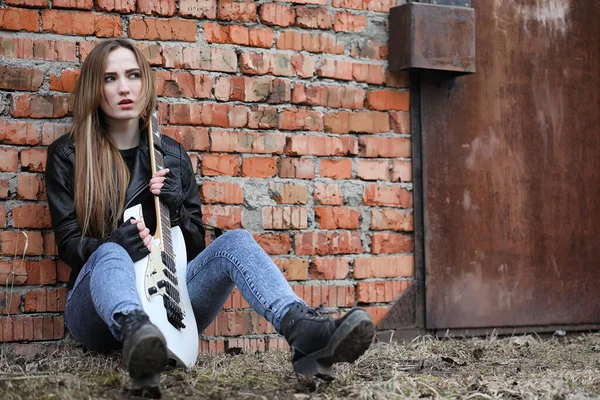 Ein Rockmusikermädchen in Lederjacke mit Gitarre — Stockfoto