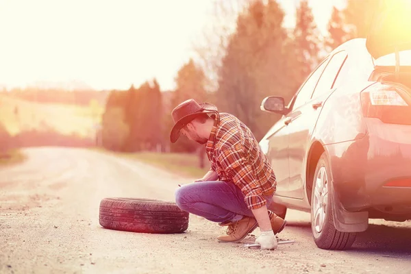 O homem está sentado na estrada junto ao carro. — Fotografia de Stock