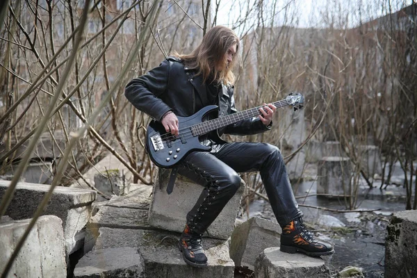 Guitarrista de rock nos degraus. Um músico com uma guitarra baixo em um — Fotografia de Stock