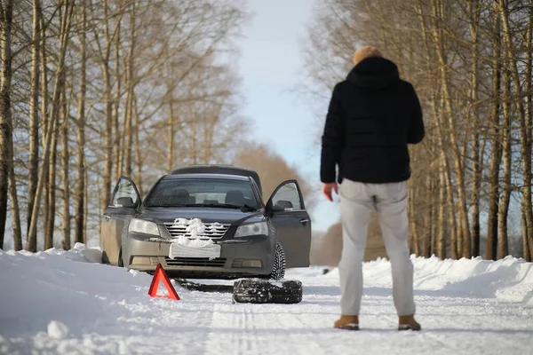 Un hombre cerca de un coche roto en un día de invierno — Foto de Stock